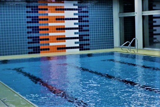 Datei:Schauwand in der Schwimmhalle der Konrad-Adenauer-Realschule mit Kacheln in den Farben hell- und dunkelblau, orange sowie weiss.jpg